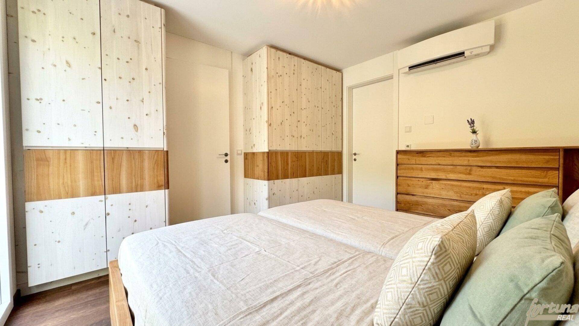 Gemütliches Schlafzimmer mit Holzelementen, Einbauschränken und Klimaanlage für Komfort.