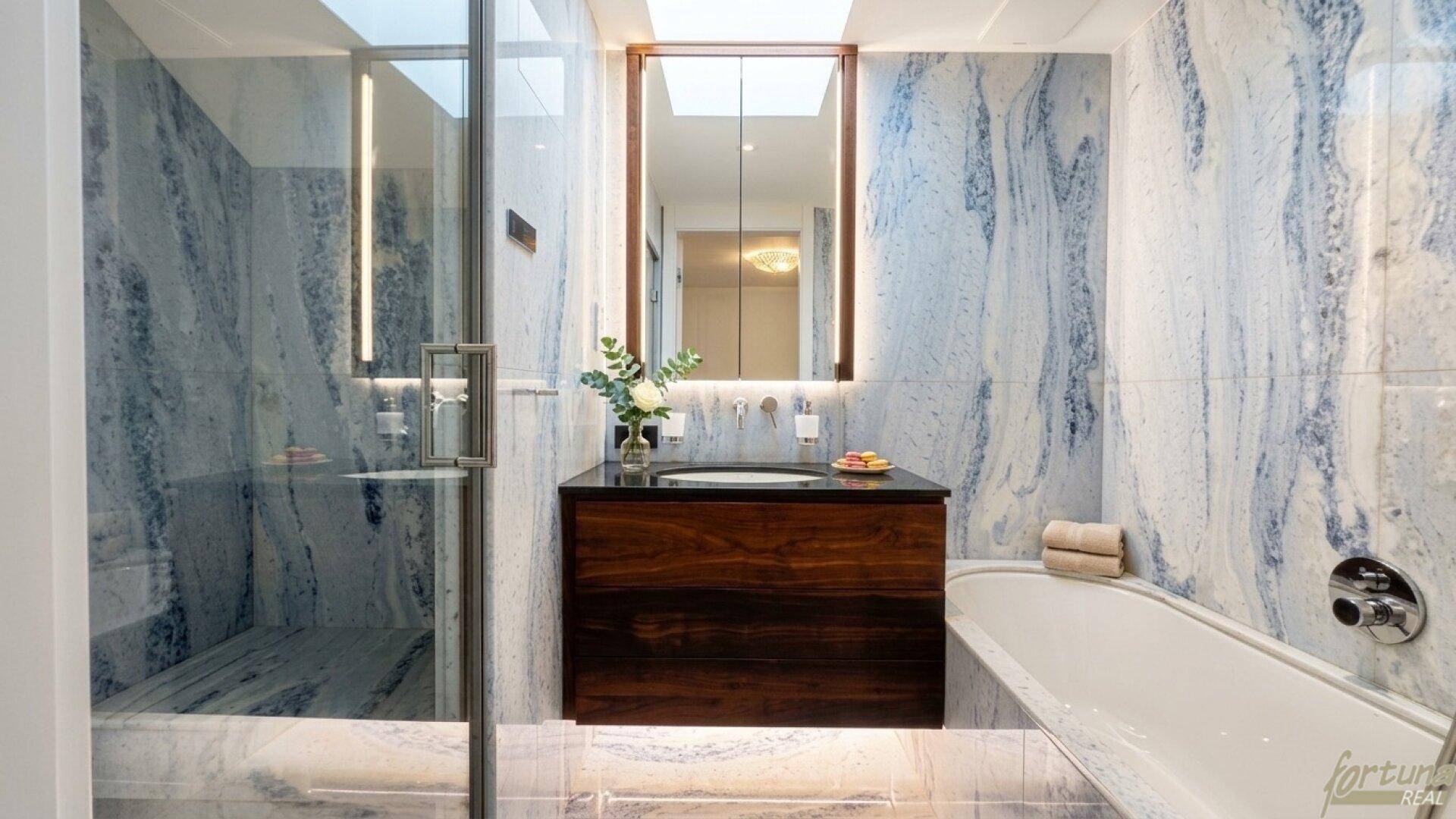 Luxuriöses Badezimmer mit blauen Marmorfliesen, Holzwaschtisch und integrierter Badewanne.
