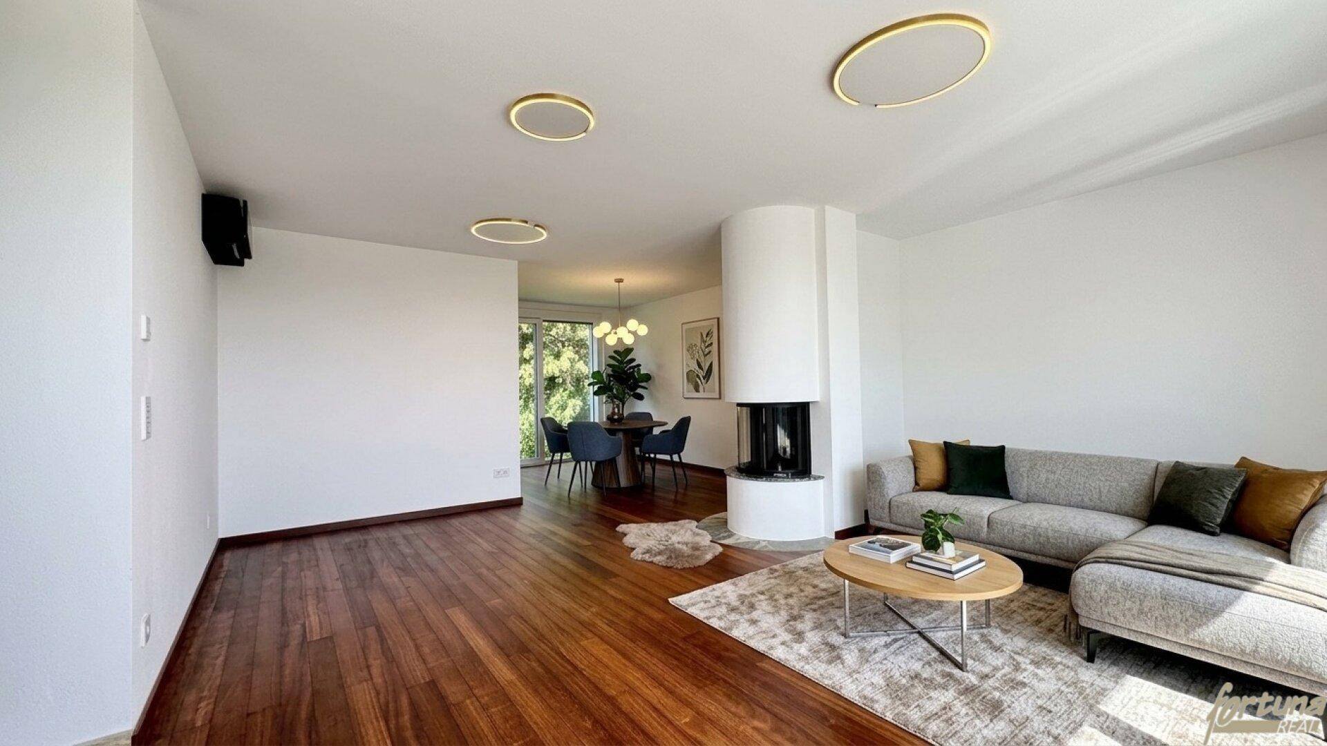 Helles Wohn- und Esszimmer mit Holzboden, modernem Kamin und Zugang zum Essbereich.