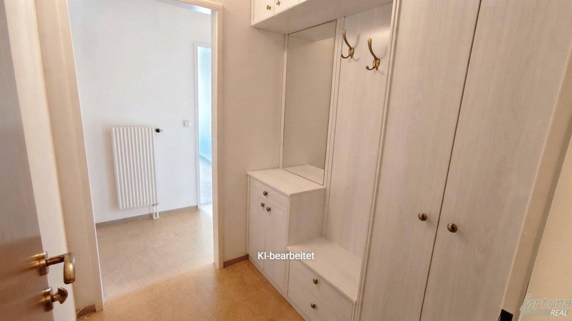 Eingangsbereich mit praktischen weißen Einbauschränken und Garderobenhaken für Kleidung.