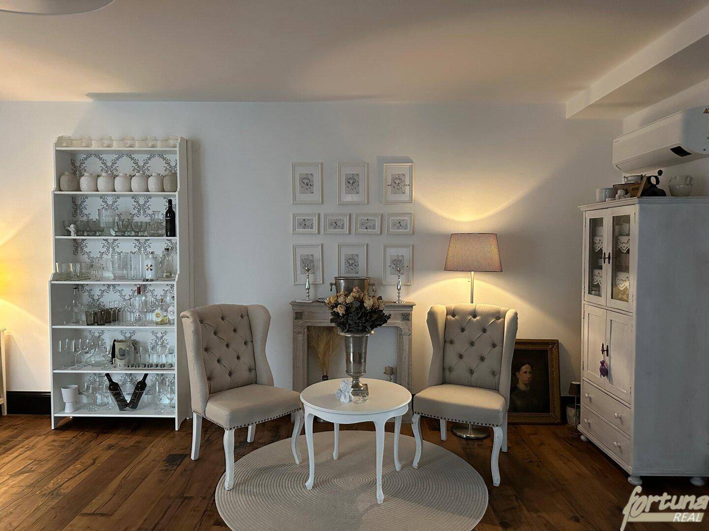 Gemütliche Sitzecke im Wohnzimmer mit zwei eleganten Sesseln und einem dekorativen Regal.