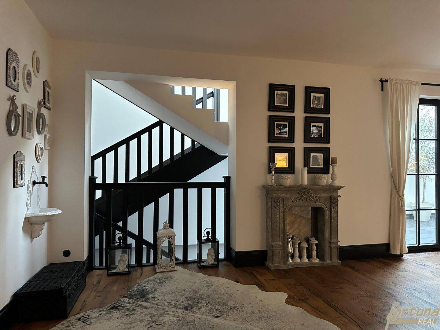 Stilvoller Flurbereich mit einer eleganten Treppe, einem dekorativen Kamin und einem Kuhfellteppich.