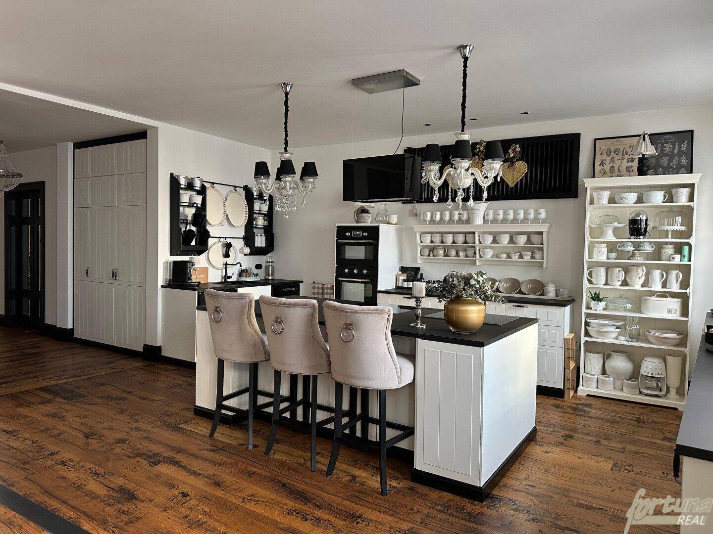 Moderne offene Küche mit großer Kücheninsel, Barhockern und eleganten weißen Schränken.