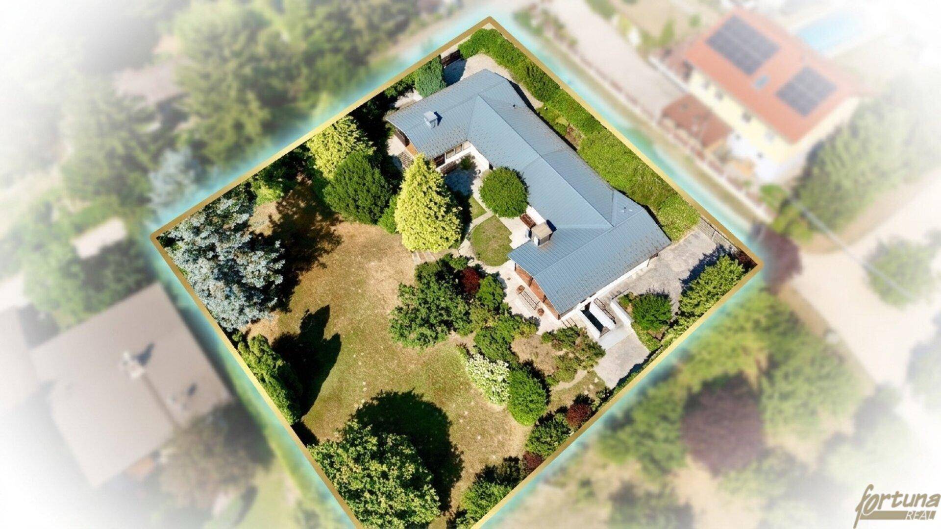 Luftaufnahme eines Einfamilienhauses mit weitläufigem, gepflegtem Garten und altem Baumbestand in einer ruhigen Wohngegend.