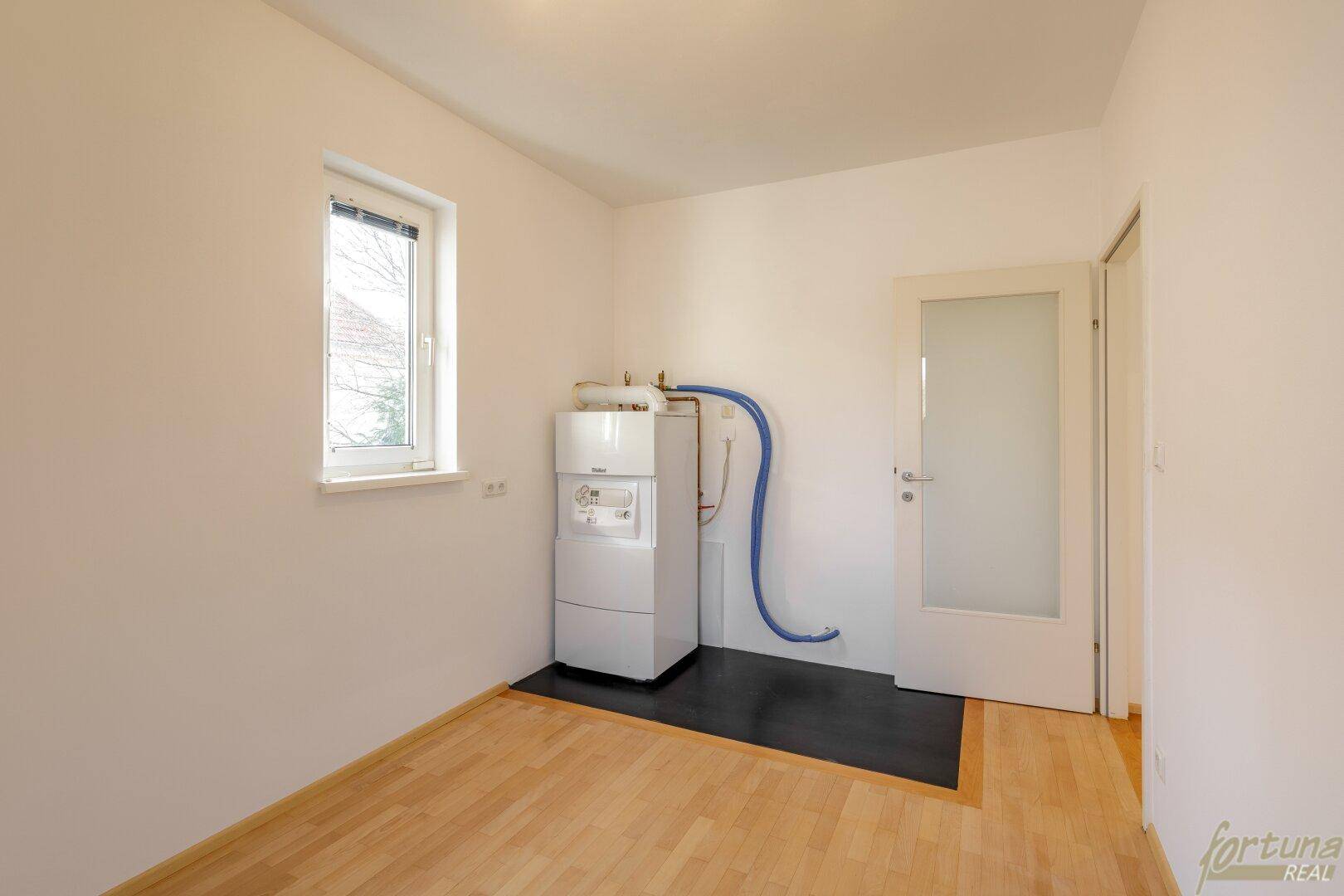 Hauswirtschaftsraum mit Heizungsanlage, Fenster und Holzboden, funktional und hell.