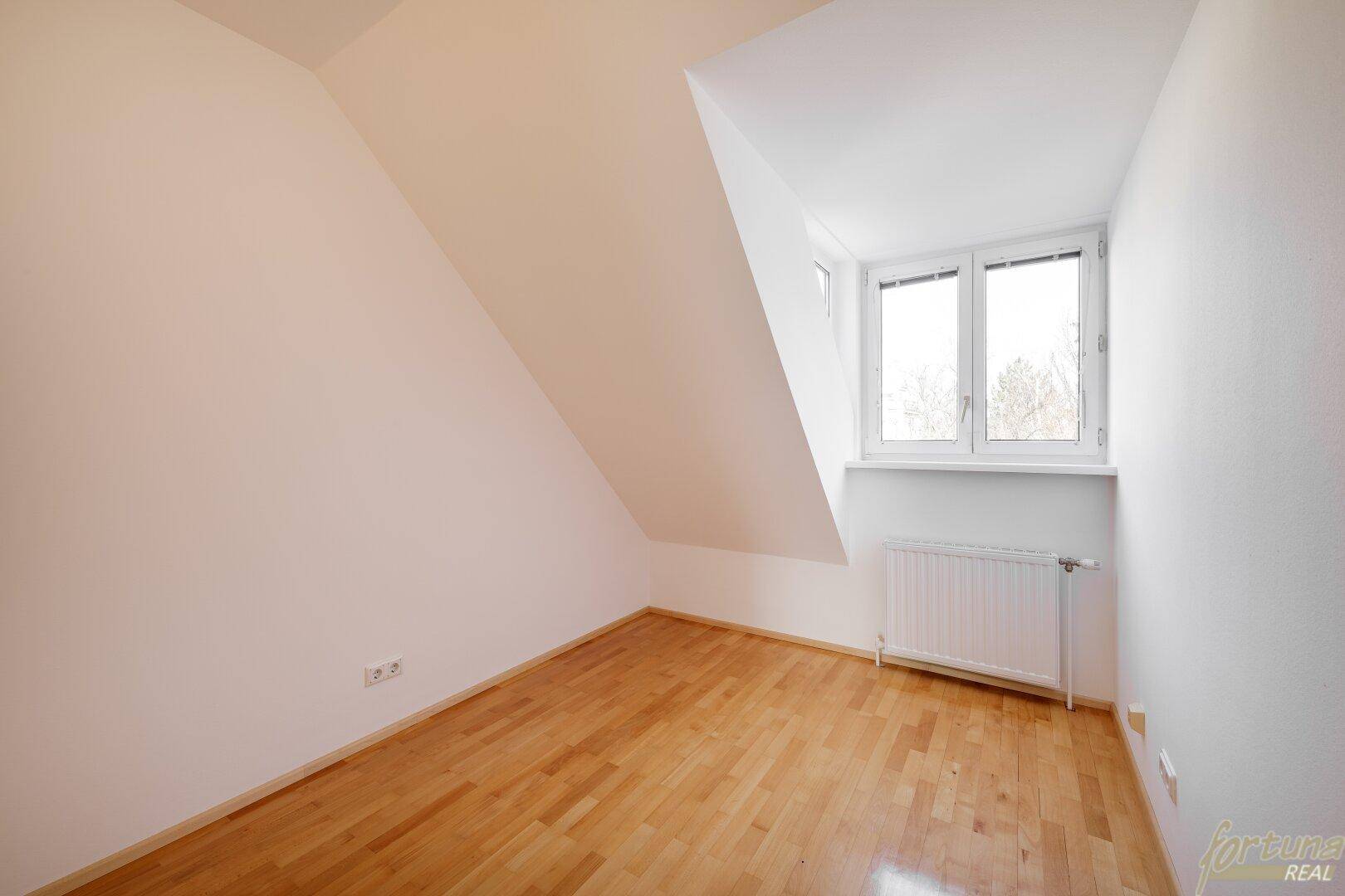 Helles Schlafzimmer mit Holzboden, Dachschräge und Fenster, ideal für ein Einzelbett.