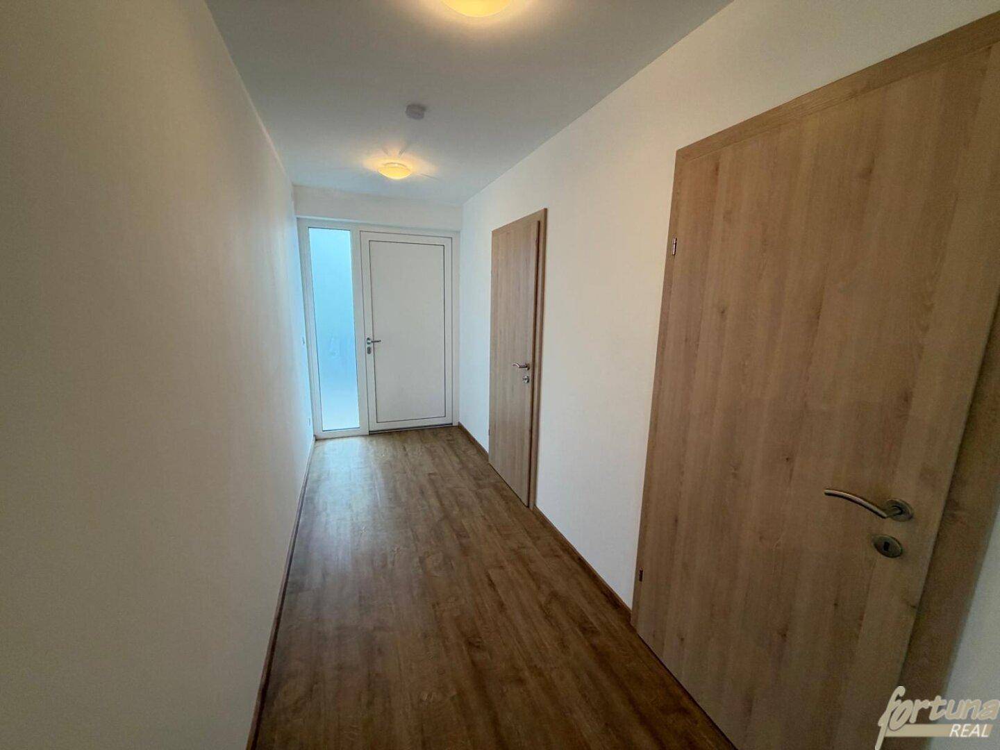 Heller Flur mit Holztüren und Laminatboden, der zu verschiedenen Räumen führt.