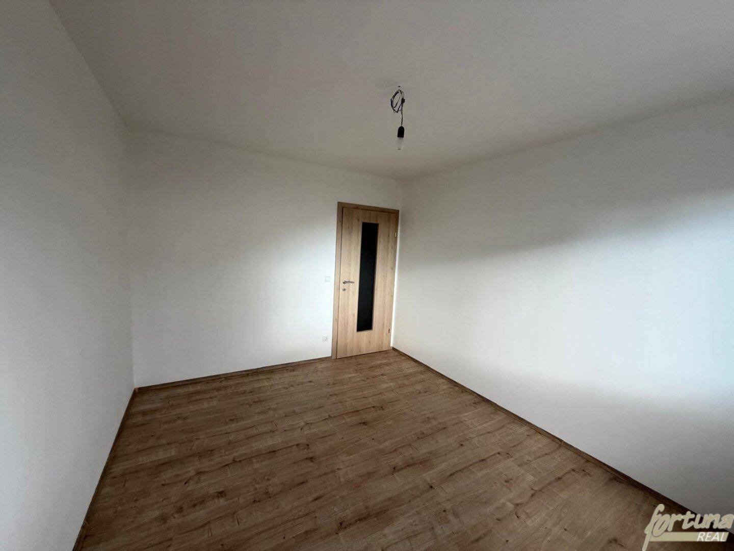 Helles Schlafzimmer mit Laminatboden und einer Holztür, bereit zur individuellen Gestaltung.