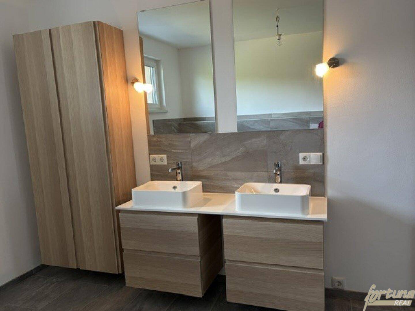 Doppelwaschbecken mit Holzunterschränken und großem Spiegel in einem modernen Badezimmer.