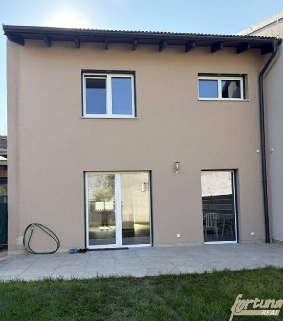 Rückseite des Hauses mit Terrasse, Rasenfläche und Zugang zum Garten.