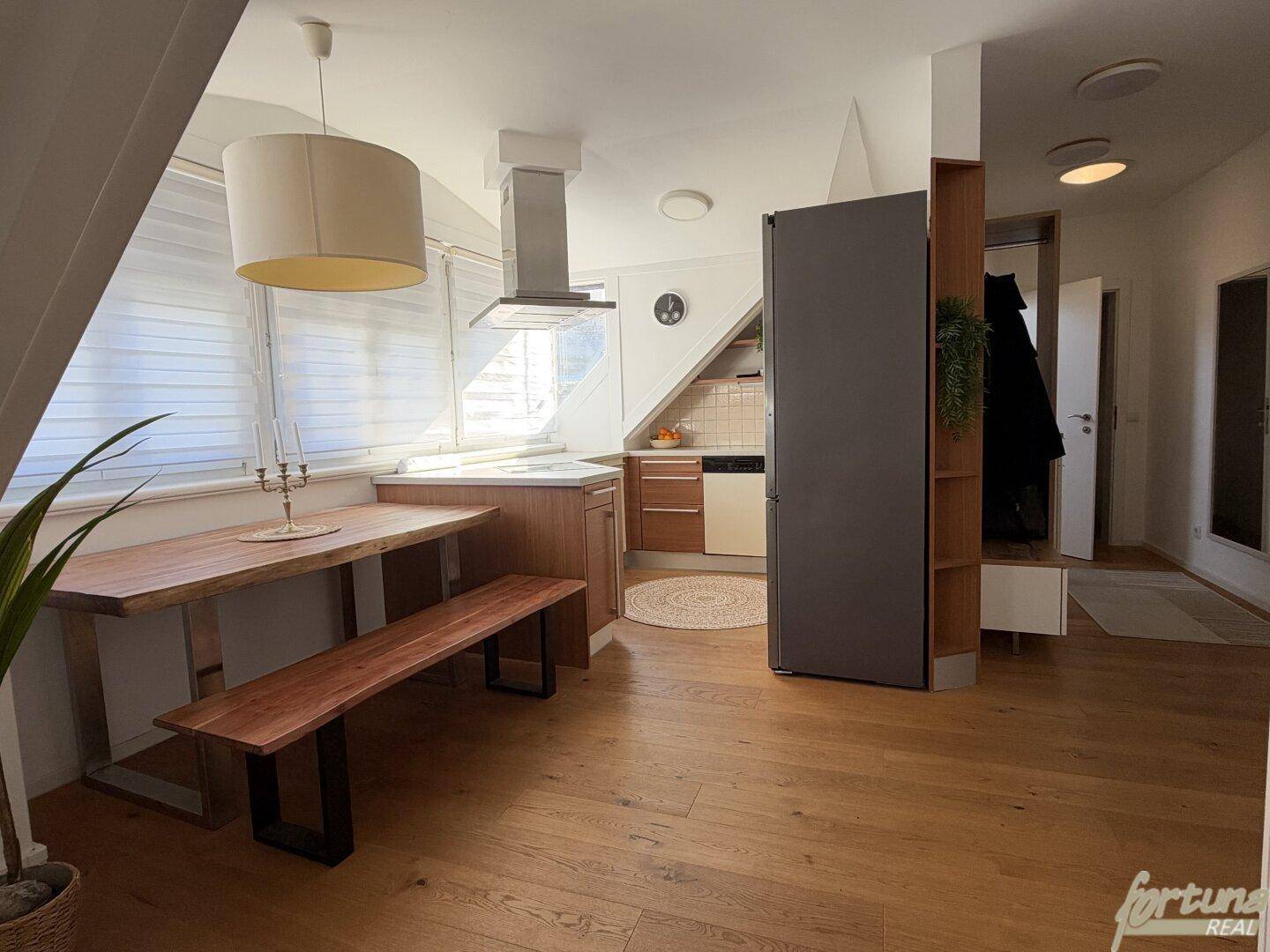 Offene Wohnküche mit Essbereich, Holzboden und modernen Geräten.