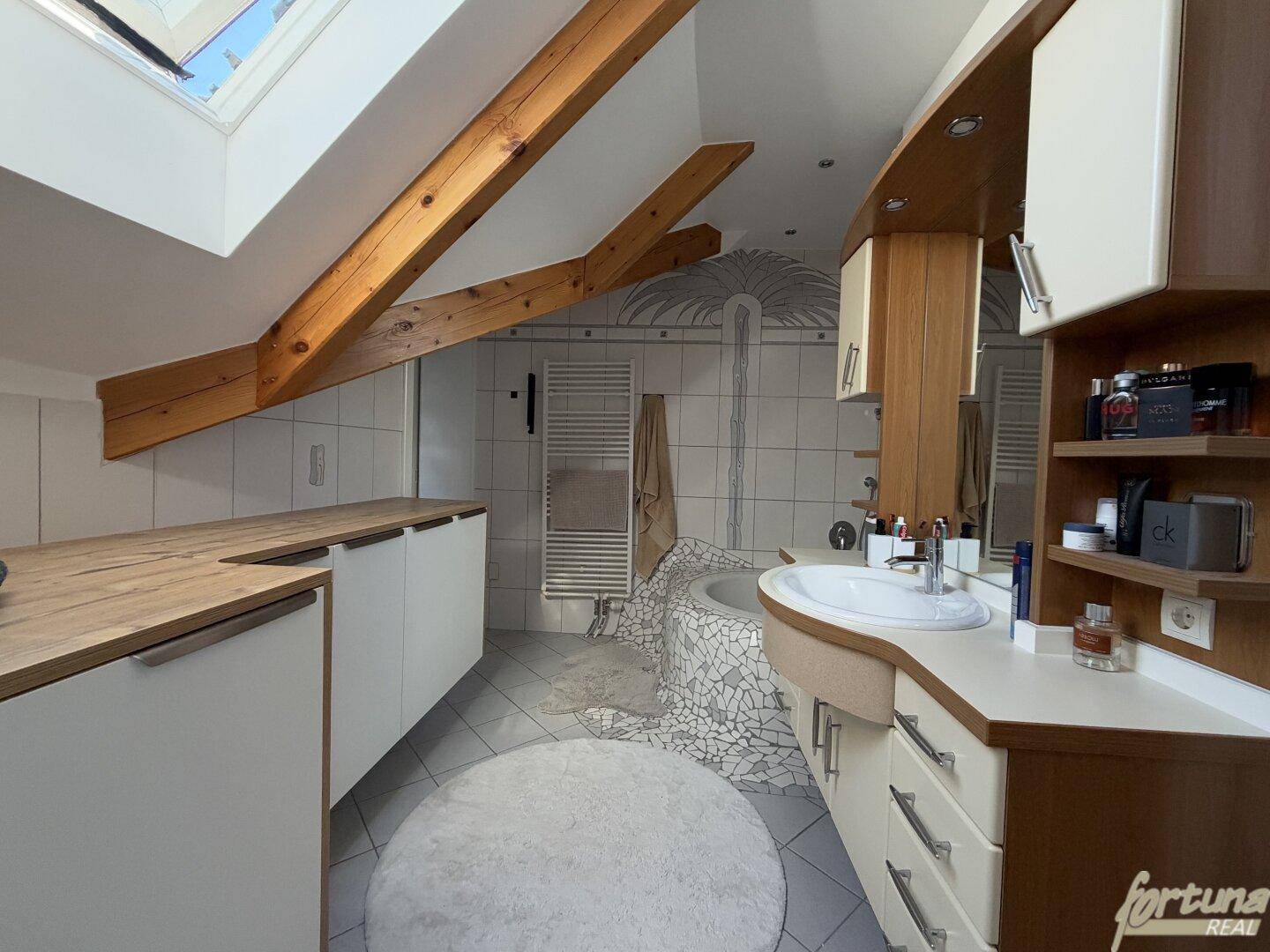 Badezimmer mit Dachschräge, Holzbalken und Badewanne.