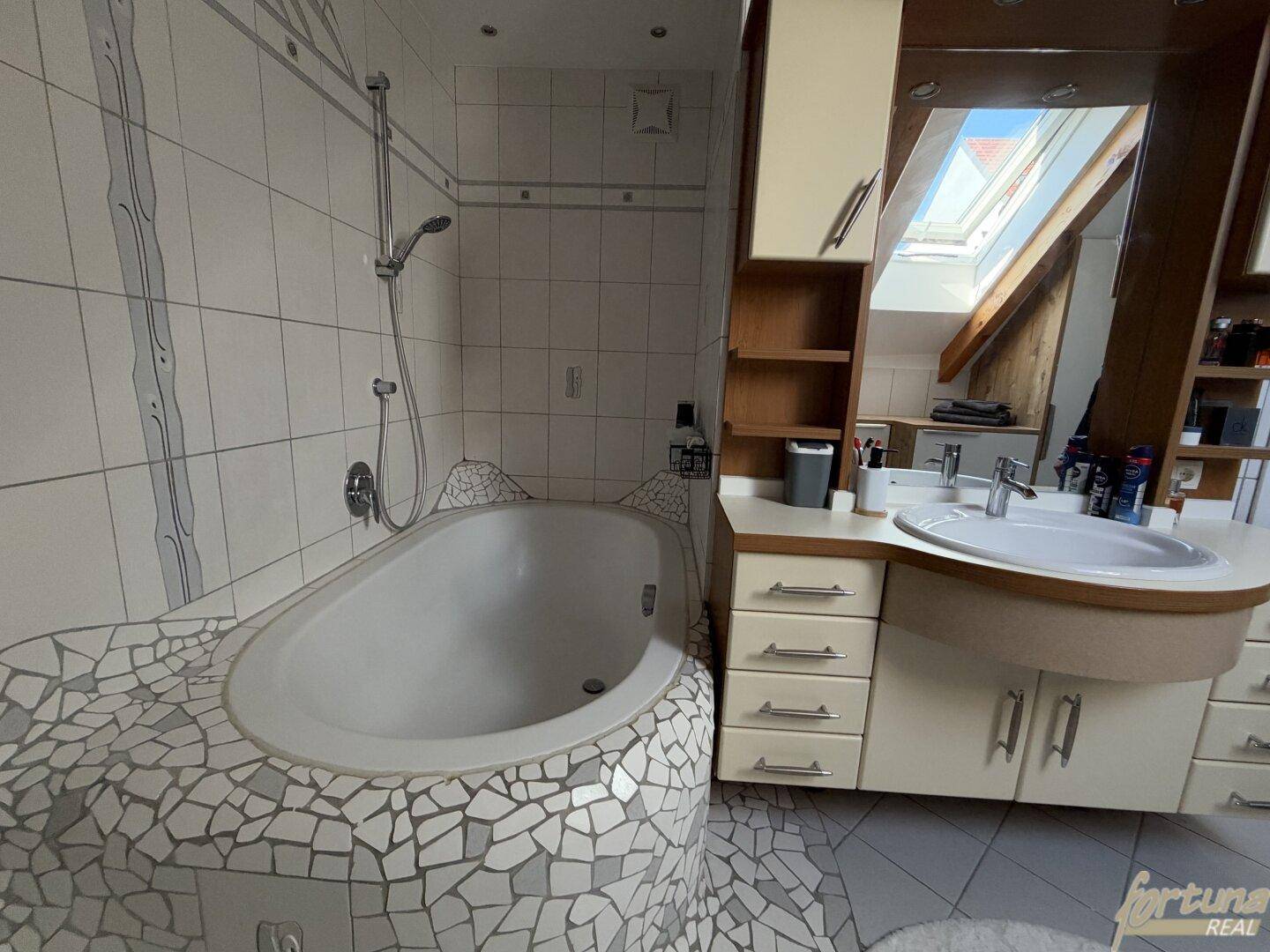 Badezimmer mit Badewanne, Dusche und Waschtisch mit Spiegel.