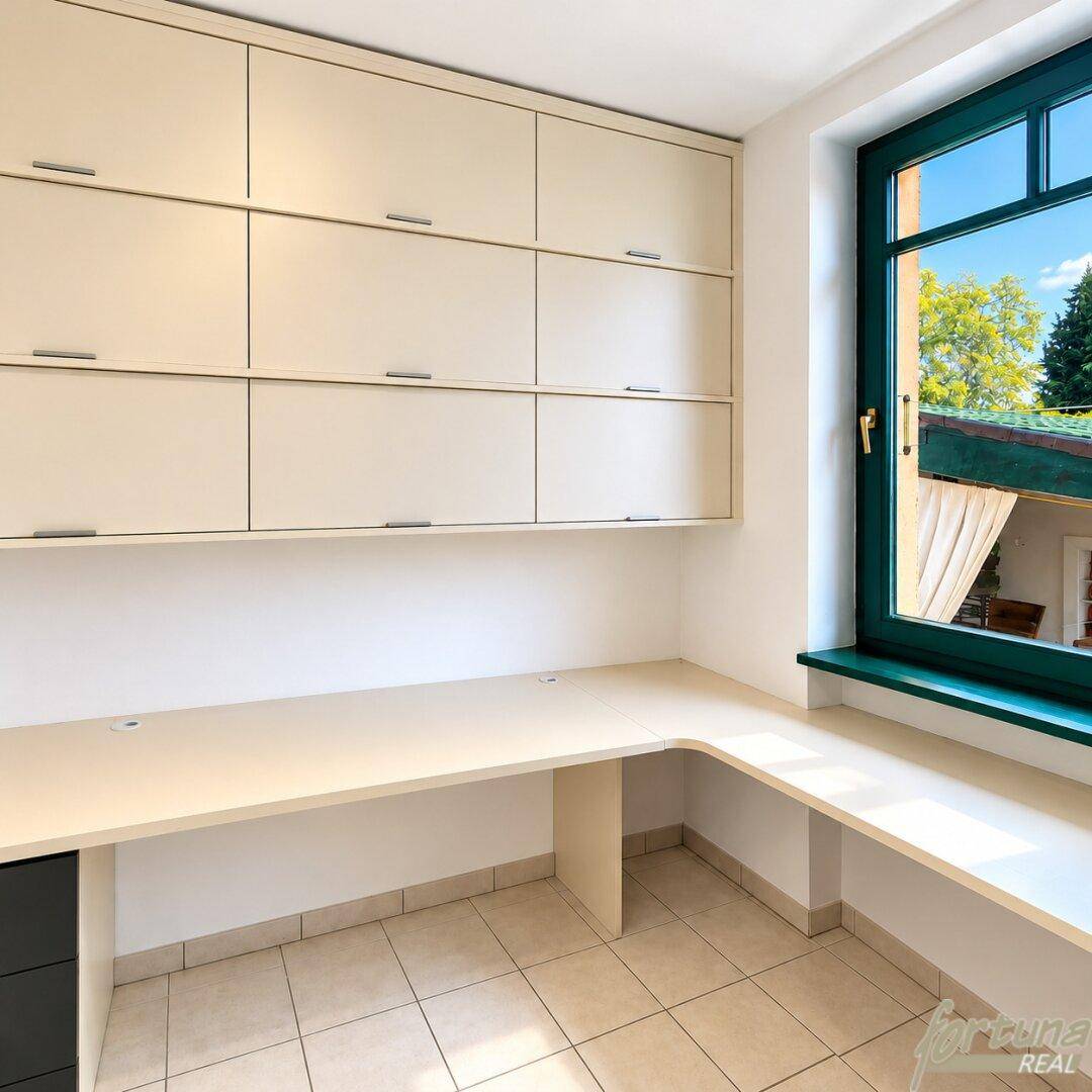Helles Arbeitszimmer mit integriertem Schreibtisch, Wandschränken und Fliesenboden.
