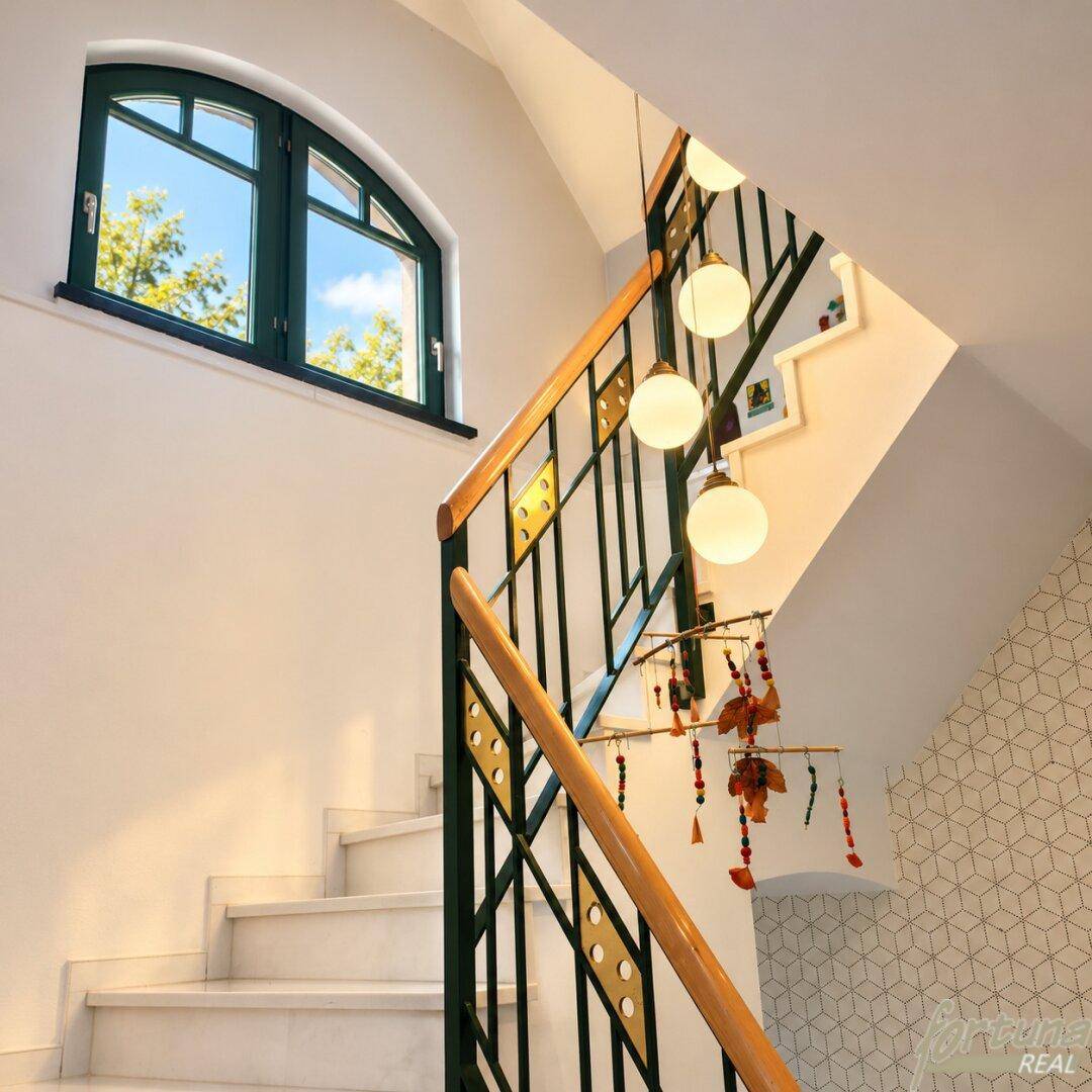 Elegantes Treppenhaus mit Marmorstufen, dekorativem Geländer und einem charmanten Bogenfenster.