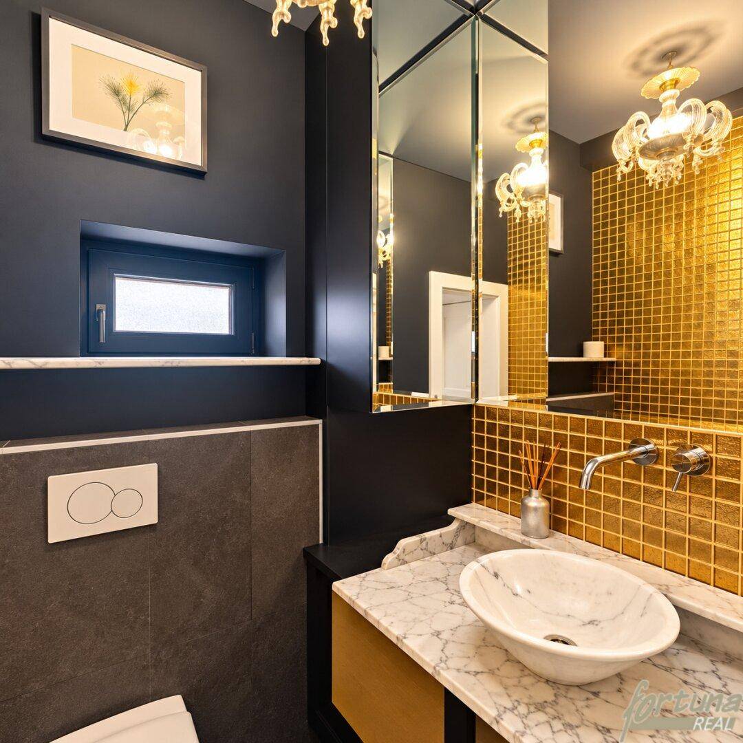 Elegantes Gäste-WC mit dunklen Wänden, goldenen Mosaikfliesen und Marmorwaschtisch.