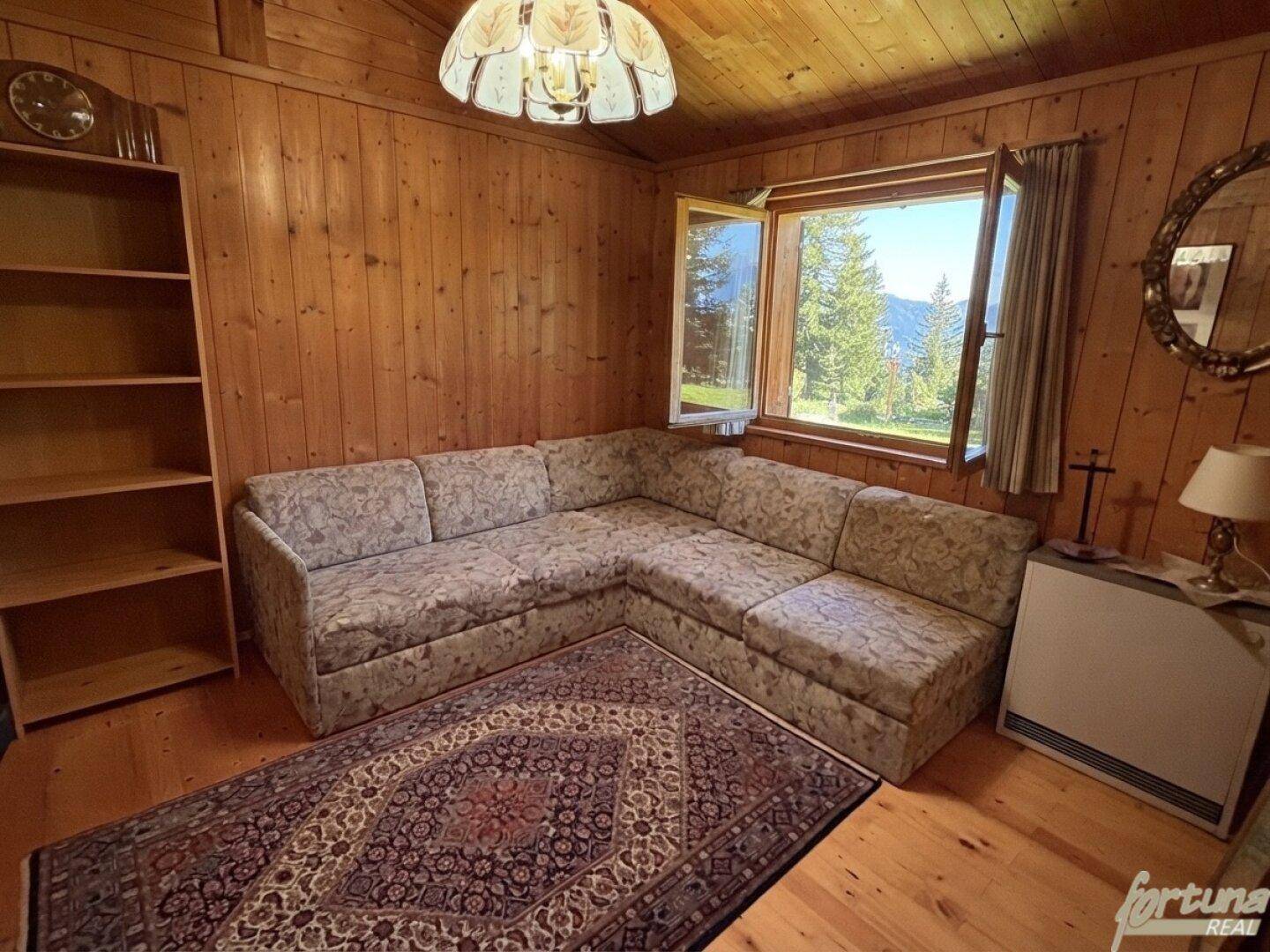 Gemütliches Wohnzimmer mit Ecksofa und Blick auf die grüne Landschaft, sehr einladend.