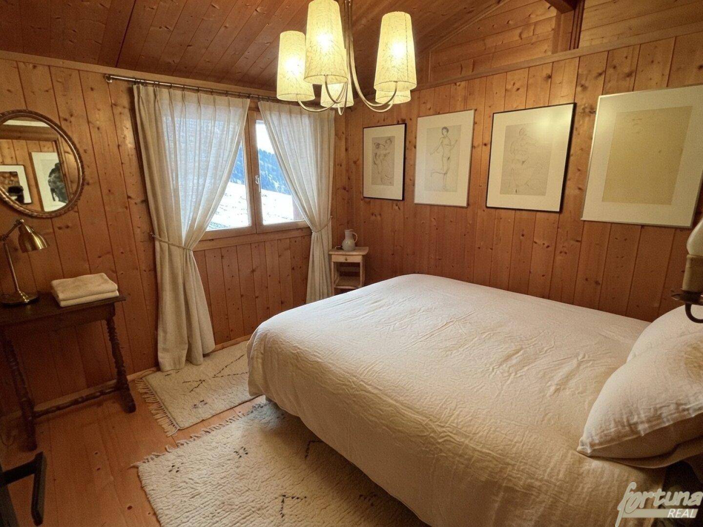 Gemütliches Schlafzimmer mit Holztäfelung, Doppelbett und Blick auf die Berge, sehr einladend.