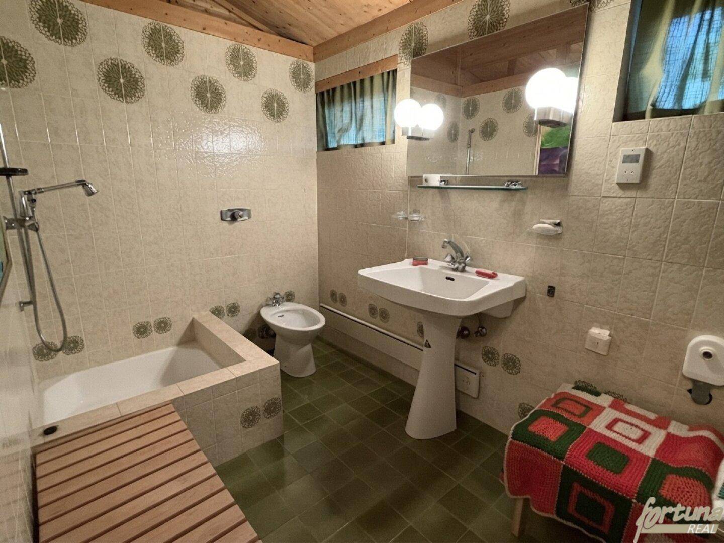 Badezimmer im 80er-Jahre-Stil mit grünen Fliesen, Badewanne und Bidet, sehr gepflegt.