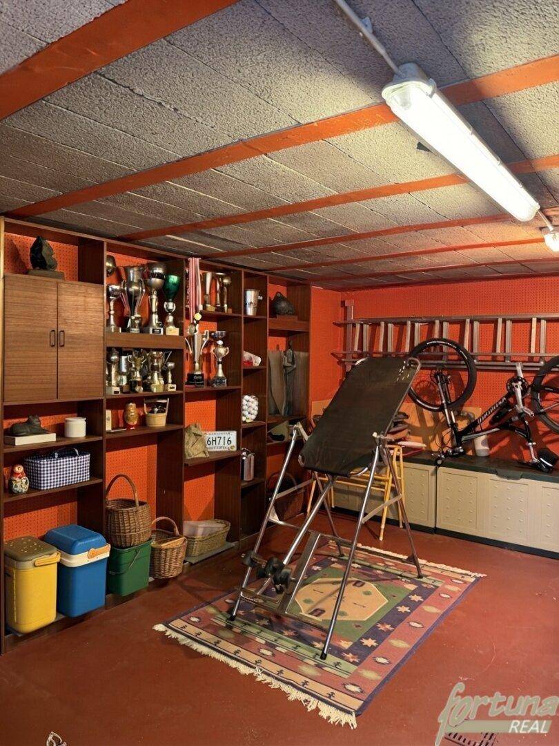 Vielseitiger Raum im Untergeschoss mit Fitnessgeräten und Stauraum, ideal für Hobbys.
