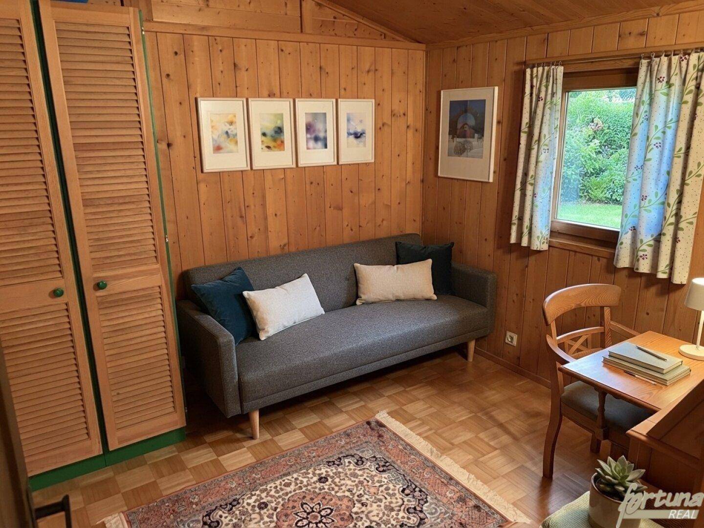 Kleines Schlafzimmer oder Gästezimmer mit Holztäfelung, Sofa und Schreibtisch, sehr funktional.