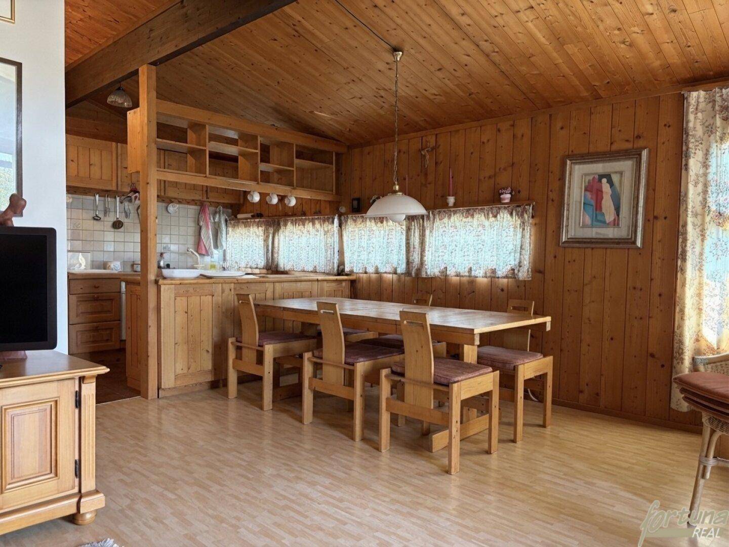 Rustikaler Wohn-Essbereich mit Holztäfelung, Esstisch und kleiner Küchenzeile, sehr gemütlich.