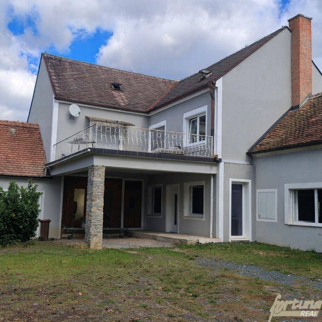 Ansicht des Gebäudes mit Balkon, überdachter Terrasse und gepflegter Fassade.