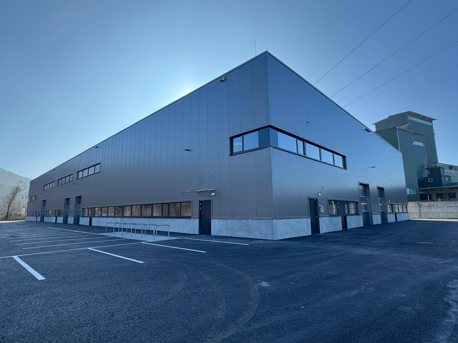 Ansicht des modernen Industriegebäudes mit großzügigen Parkflächen und klarem Himmel.