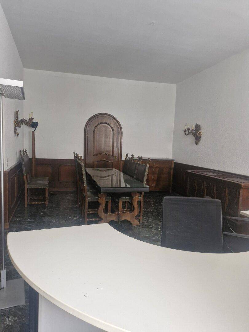 Büro mit dunklem Marmorboden, einem großen Schreibtisch und einem traditionellen Holztisch mit Stühlen.