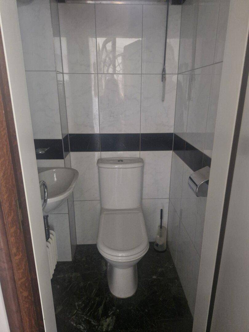Kleines Gäste-WC mit weiß-schwarzen Fliesen, einem Waschbecken und einer Toilette.