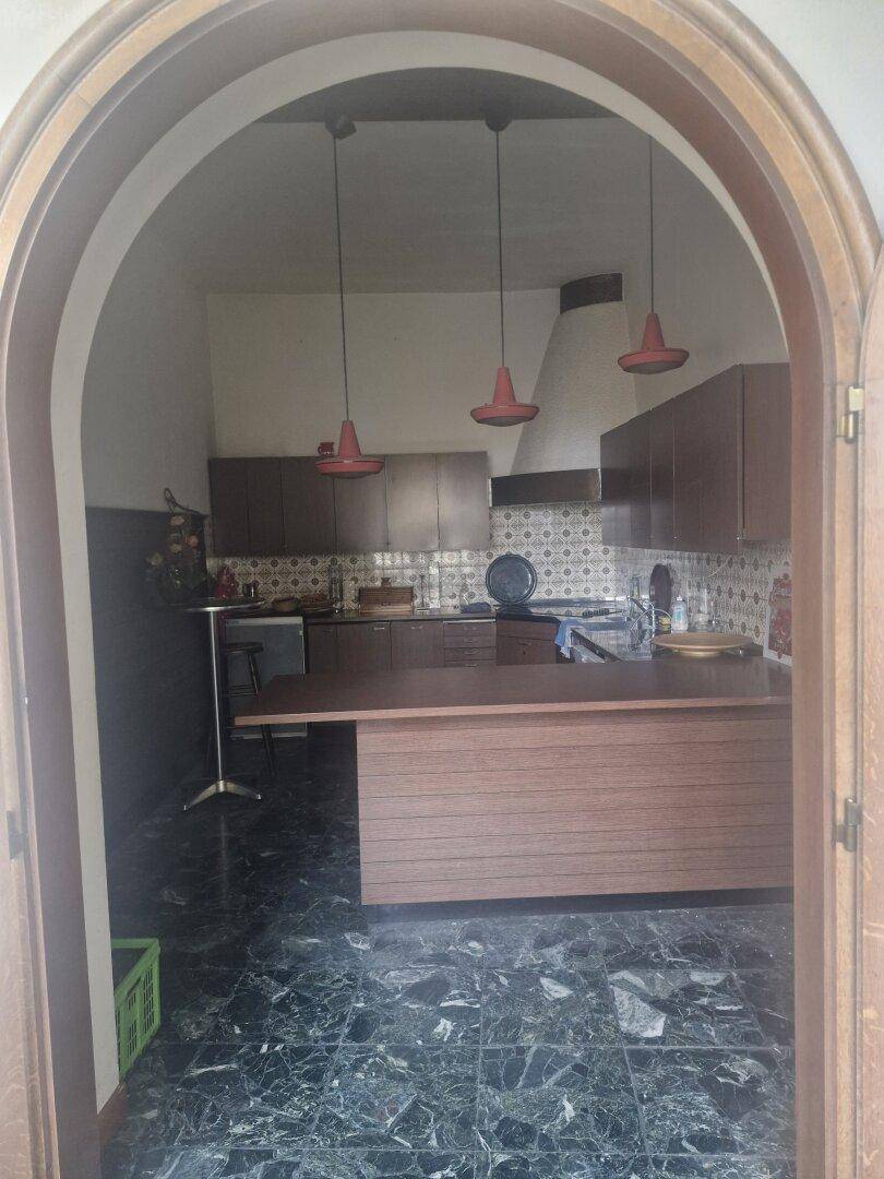 Küche mit dunklen Holzschränken, einer Kochinsel und roten Hängelampen über dem Tresen.