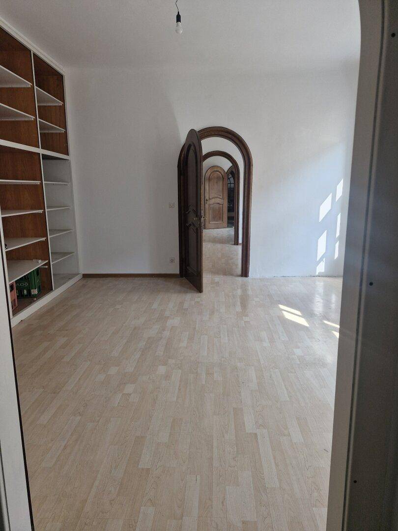 Geräumiger Raum mit hellen Einbauregalen, Laminatboden und einer Reihe von Rundbogen-Türen.