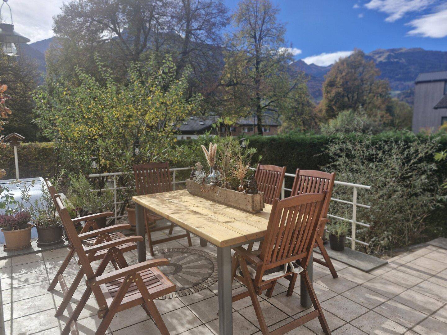 Sonnige Außenterrasse mit Esstisch und Stühlen, ideal für Mahlzeiten im Freien mit Bergblick.