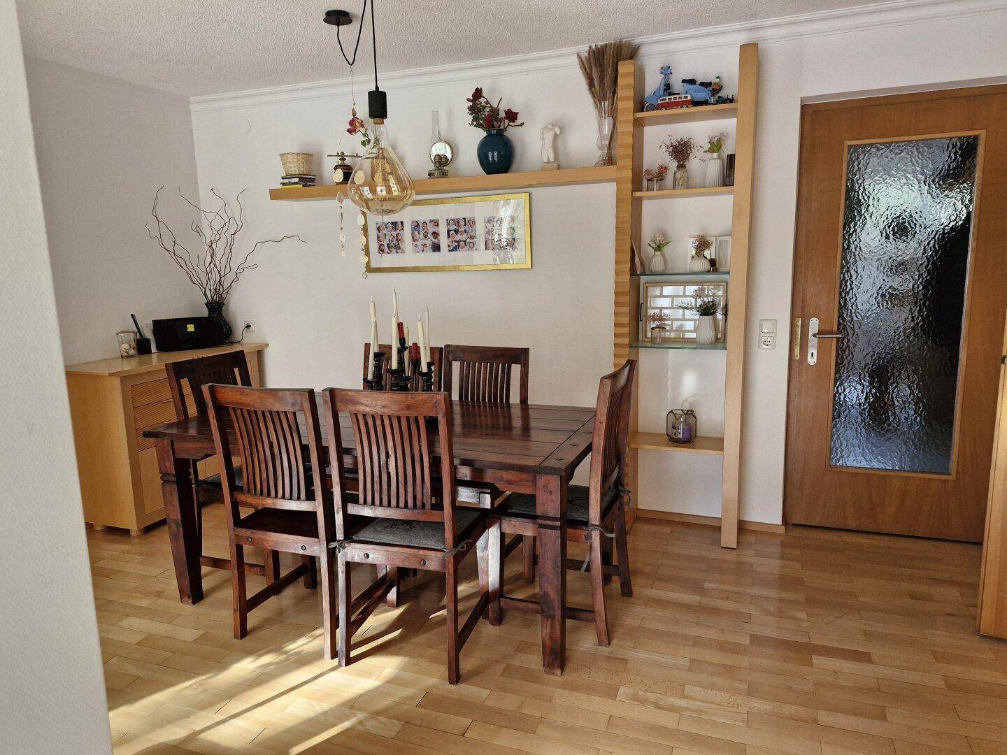 Gemütlicher Essbereich mit dunklem Holztisch, passenden Stühlen und dekorativen Regalen.