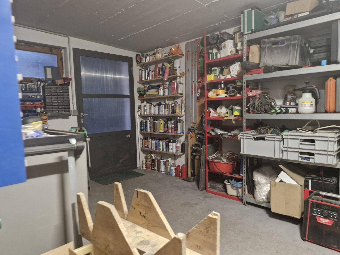 Geräumiger Werkstatt- oder Abstellraum mit Regalen voller Werkzeuge und Materialien.