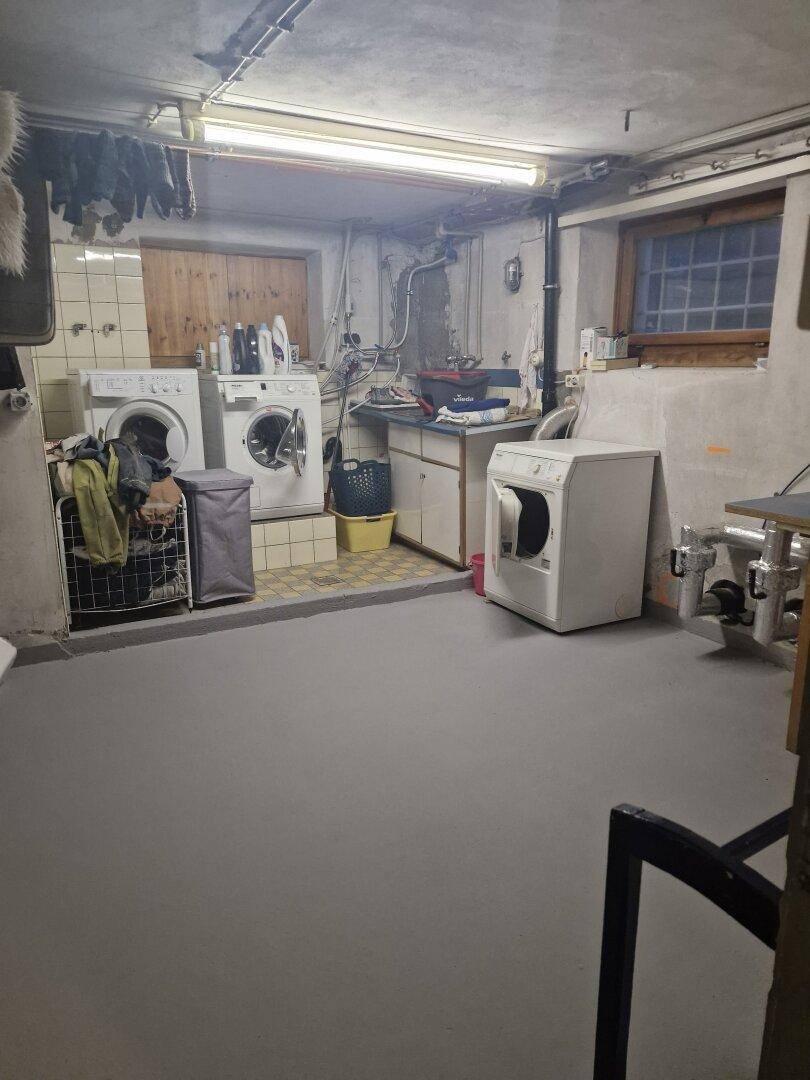 Funktionaler Hauswirtschaftsraum im Keller mit Waschmaschinen, Trockner und Spülbecken.