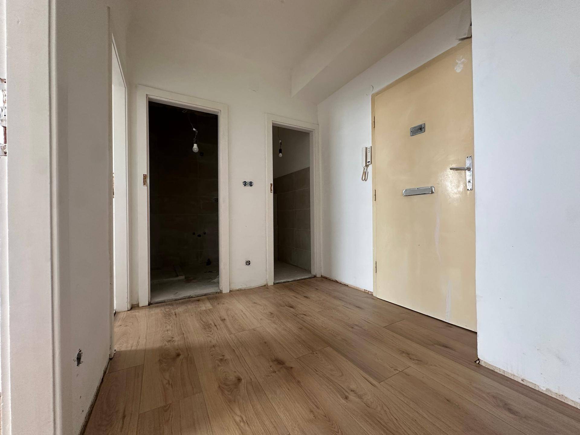 Heller Flur mit Laminatboden und mehreren Türen, der den Zugang zu verschiedenen Räumen ermöglicht.