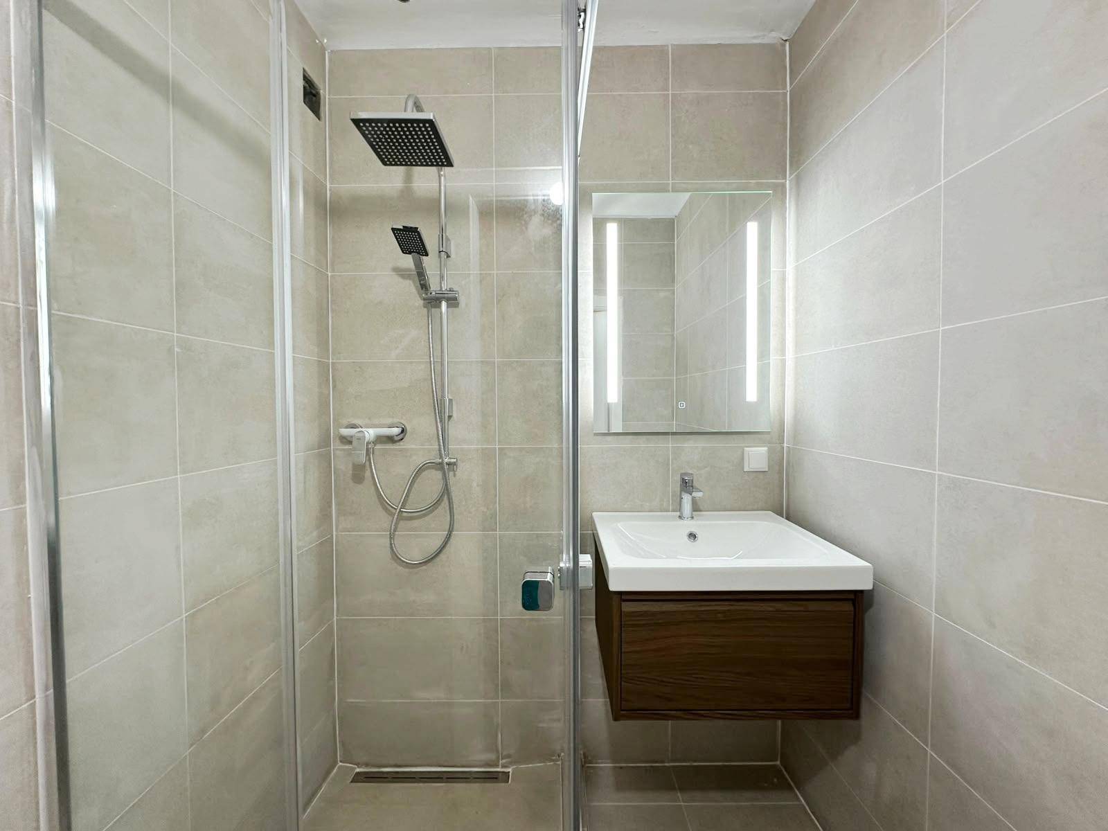Modernes Badezimmer mit begehbarer Dusche, Regendusche und schwebendem Waschtisch mit beleuchtetem Spiegel.