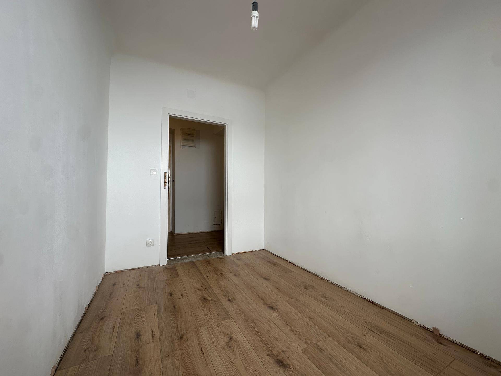 Unmöblierter Raum mit hellem Laminatboden und weiß gestrichenen Wänden, ideal für verschiedene Nutzungen.