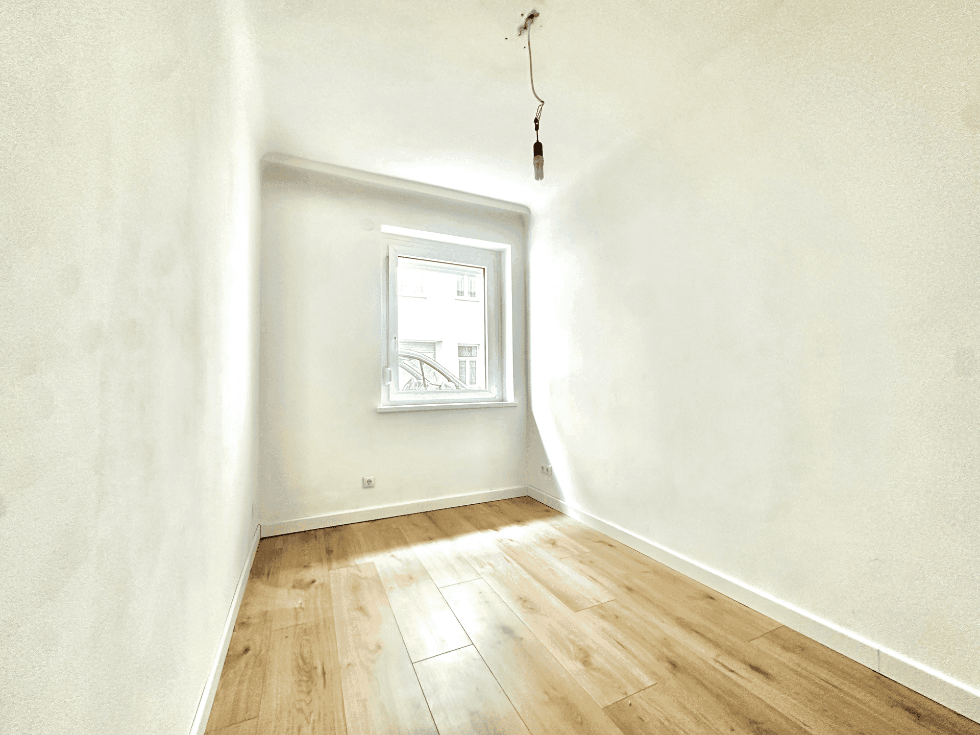 Kleinerer, heller Raum mit Holzboden und Fenster, gut geeignet als Schlafzimmer oder Arbeitszimmer.