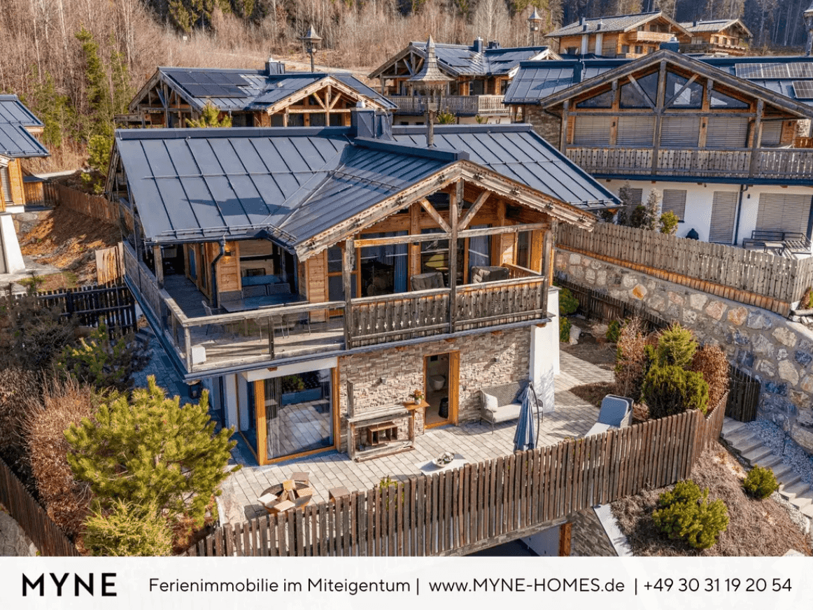 Luftaufnahme eines luxuriösen Chalet-Anwesens mit mehreren Gebäuden und alpiner Architektur in sonniger Lage.