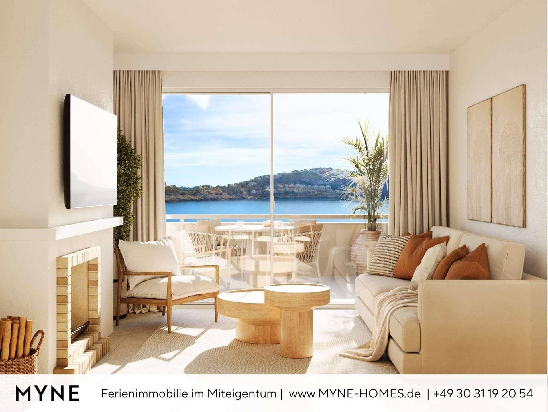 Helles Wohnzimmer mit gemütlichem Sofa, Kamin und großen Fenstern mit Meerblick.