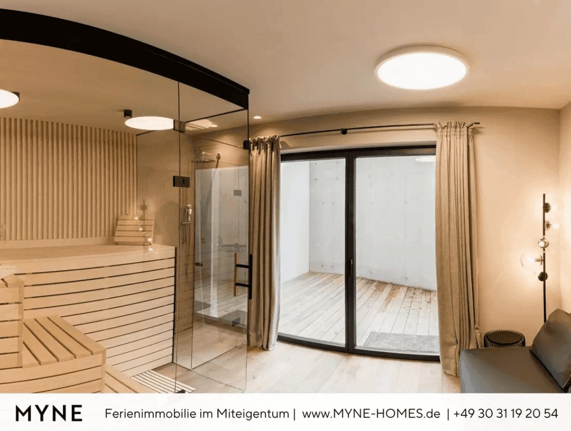 Wellnessbereich mit Sauna, moderner Dusche und Zugang zu einem kleinen Außenbereich.