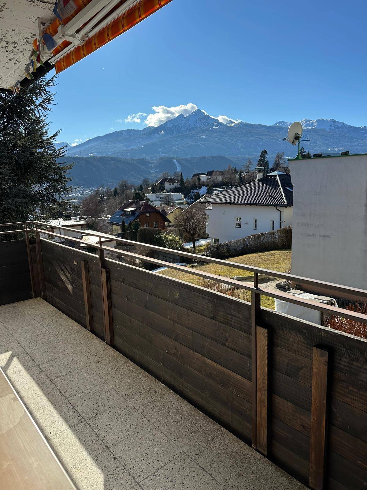 Sonniger Balkon mit Fliesenboden und weitem Panoramablick auf die Berge und die Umgebung.