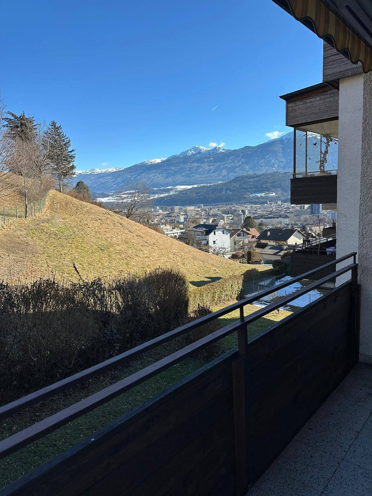 Balkon mit weitem Blick über das Tal, die Stadt und die schneebedeckten Berge im Hintergrund.