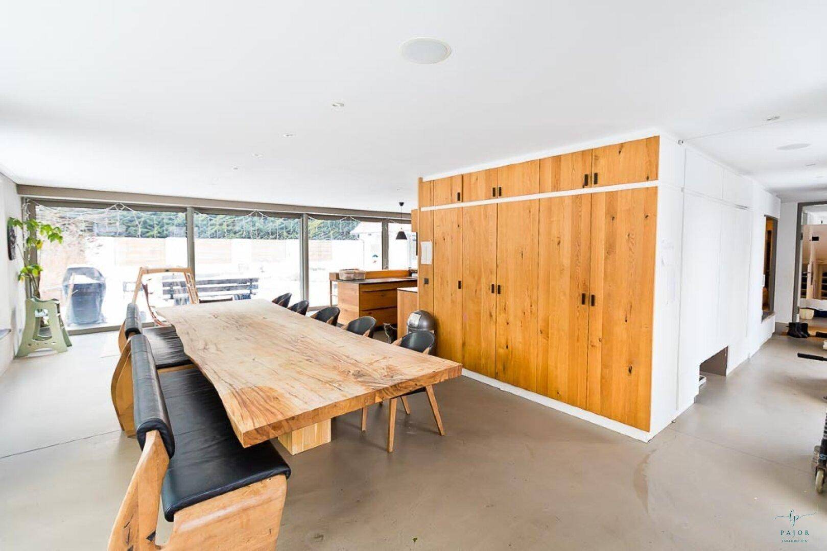 Heller Essbereich mit großem Holztisch und integrierten Holzschränken entlang der Wand.
