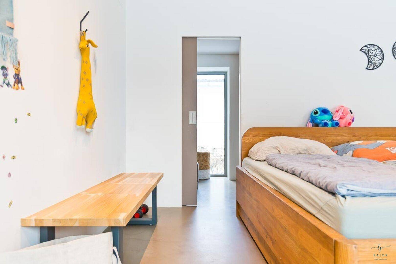 Helles Schlafzimmer mit Holzbettrahmen und weiß gestrichenen Wänden, ideal für Kinder.