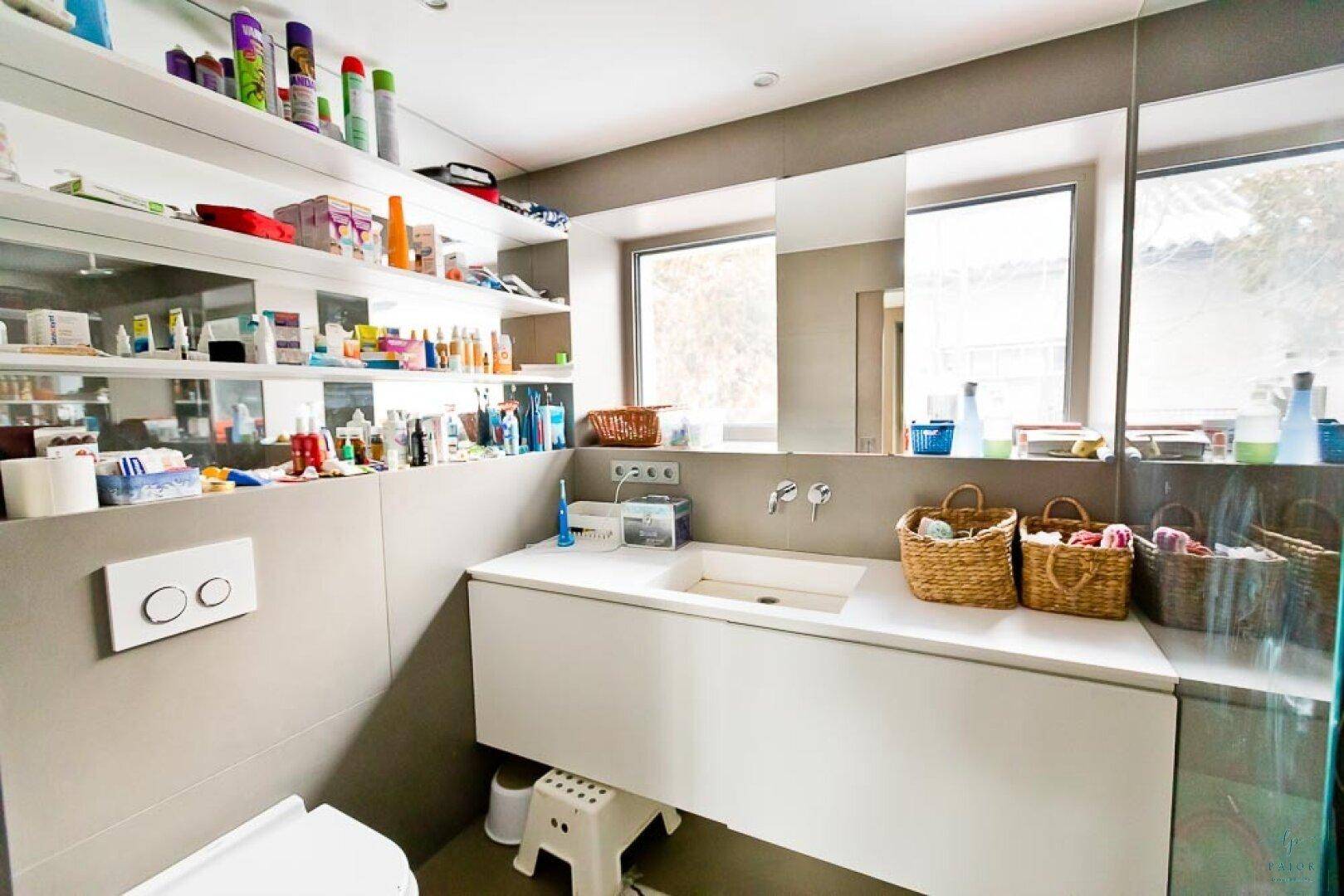 Modernes Gäste-WC mit Einzelwaschbecken, Spiegelschrank und praktischen Ablageflächen.
