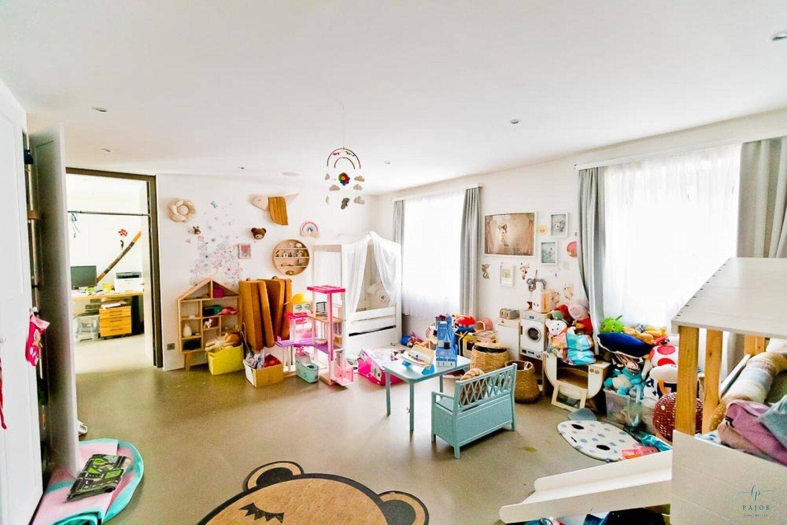 Helles Kinderzimmer mit vielen Spielsachen, einem kleinen Bett und einem Spielhaus.