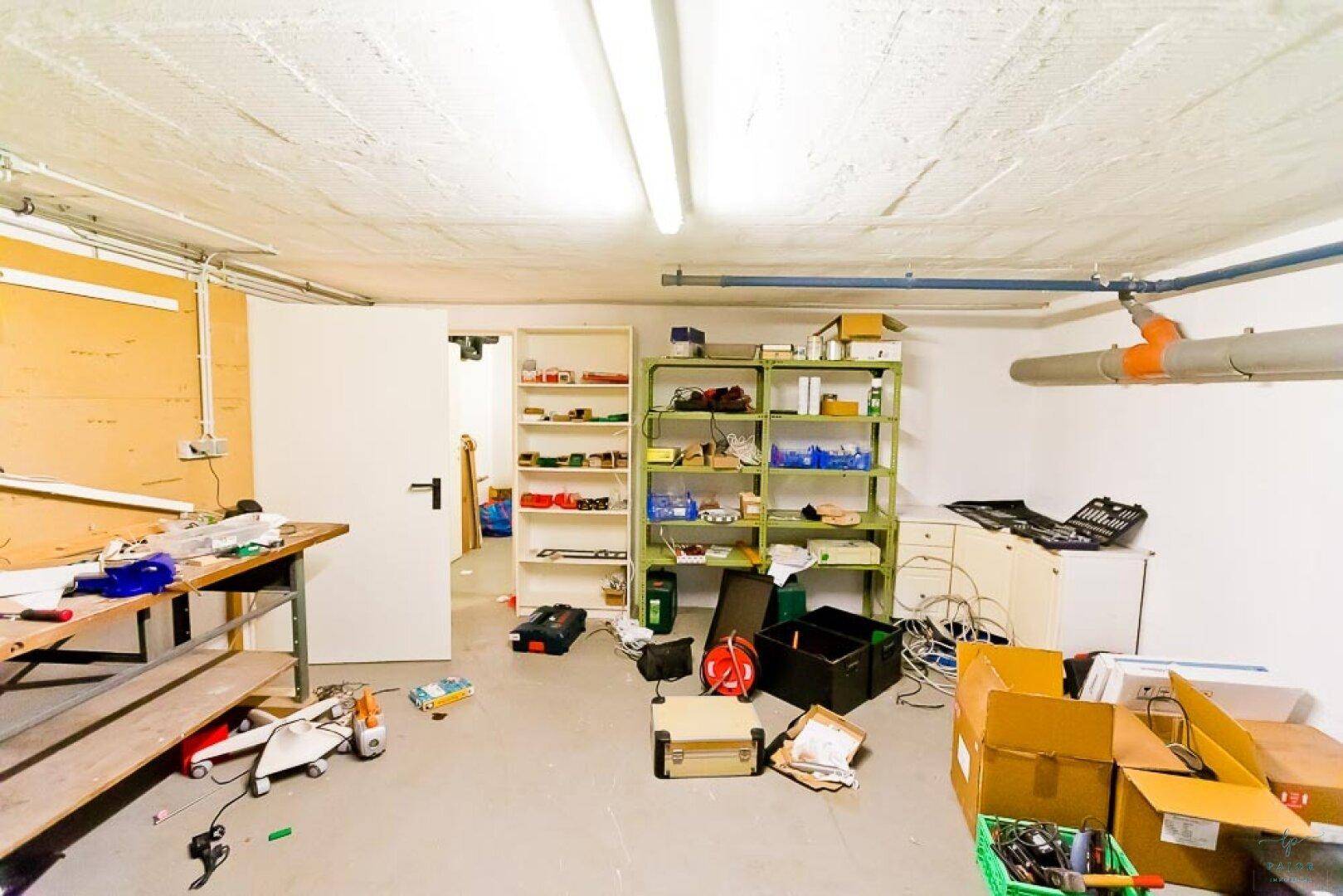 Funktionaler Kellerraum, genutzt als Werkstatt mit Regalen und Arbeitsflächen.